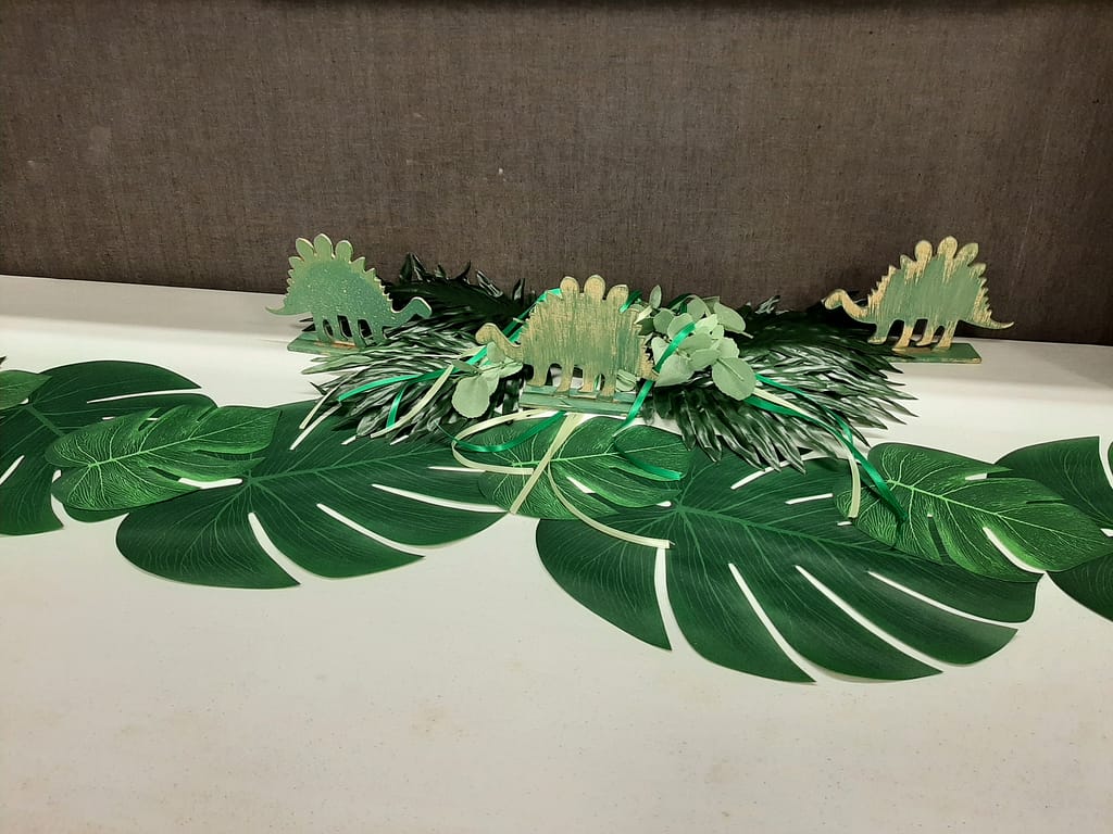 gift table at dinosaur baby shower with big tropical leaves
