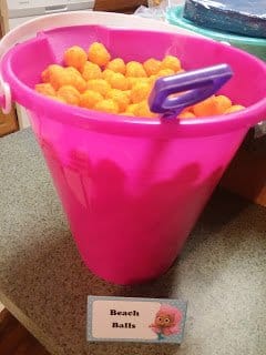 pink plastic pail filled with cheese balls with beach ball sign
