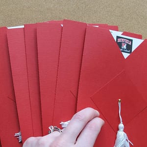 a pile of red cap and gown graduation announcements