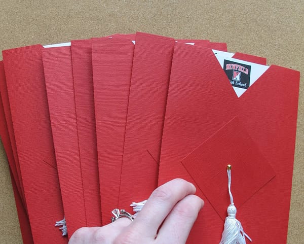 a pile of red cap and gown graduation announcements