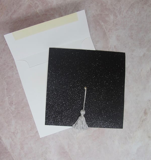 black glitter graduation invitation with white envelope