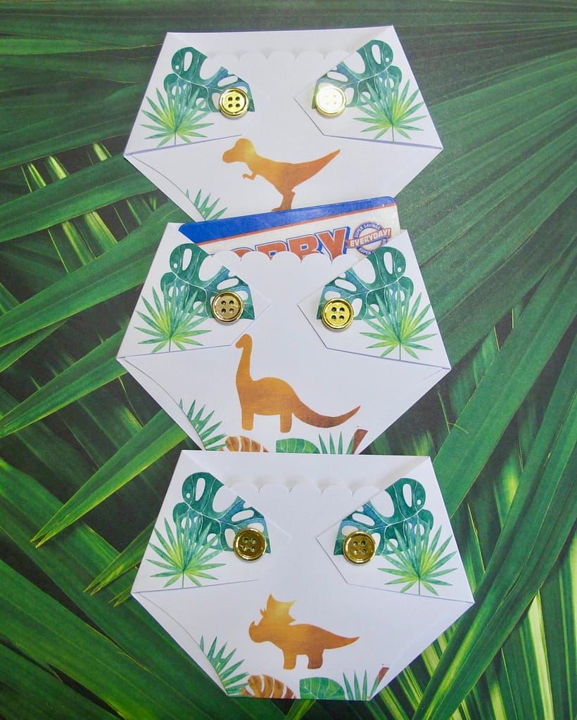 three diaper shaped gift card holders with dinosaurs and gold buttons
